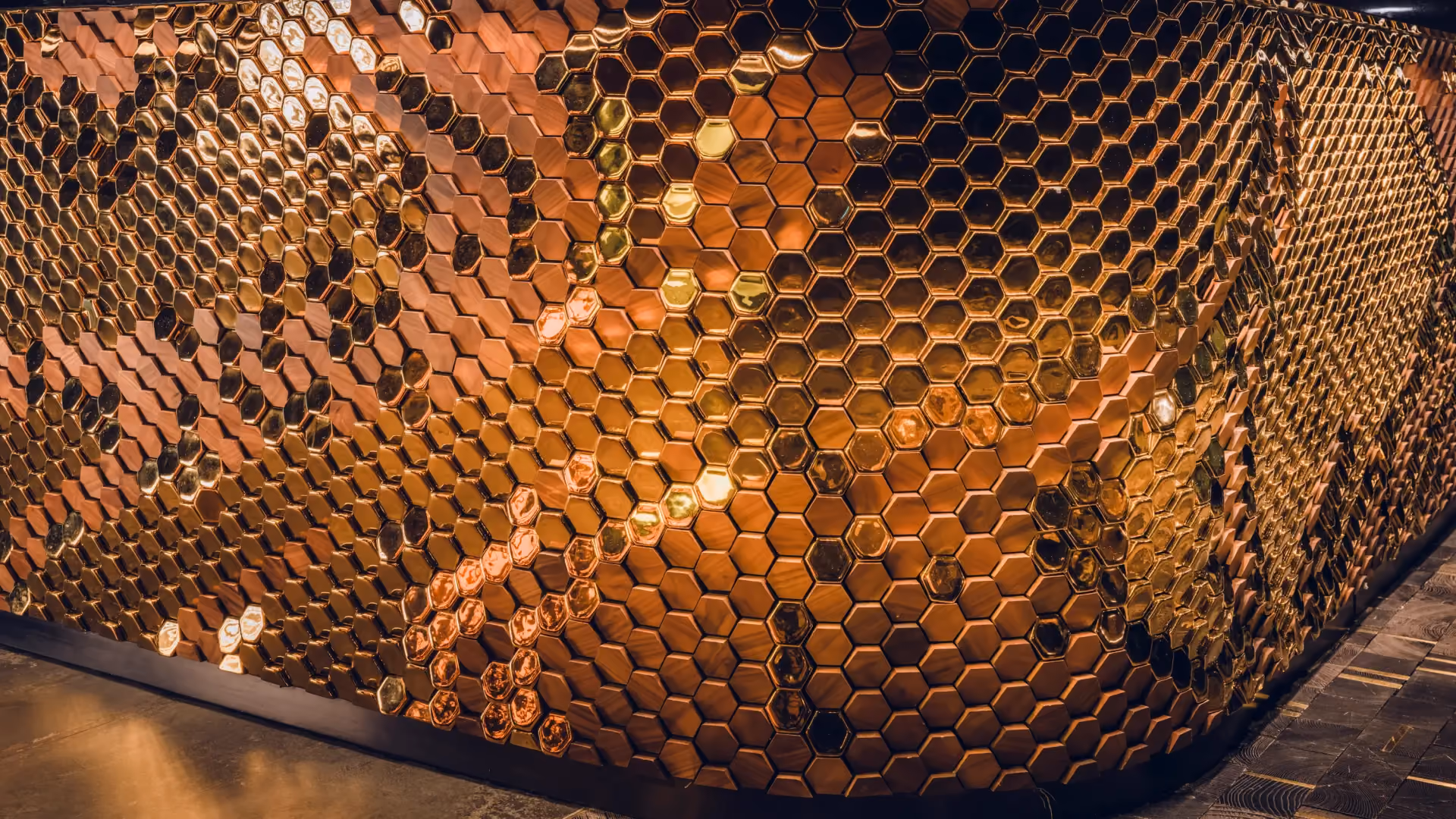 Close-up of gloss gold hexagonal Giles Miller tiles reflecting warm light at Strawfire, Emirates Palace Abu Dhabi