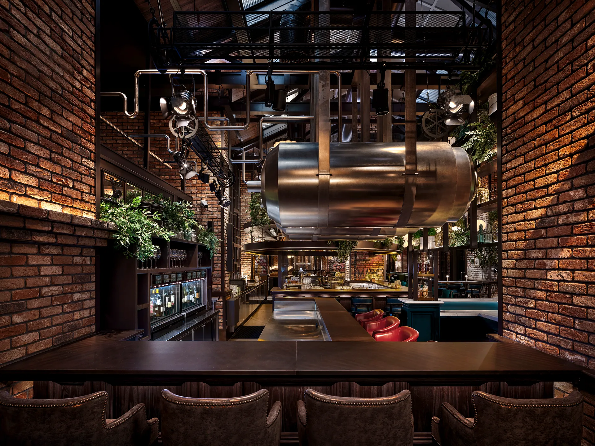View to the main bar at Broadway, Emirates Palace Abu Dhabi, past a suspended steel brewery vat, brick walls and counter seating
