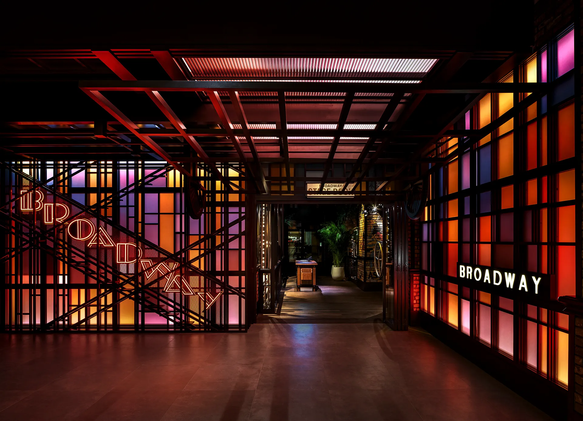 Entrance to Broadway at Emirates Palace Abu Dhabi, with neon Broadway signage on a fire escape staircase frame and backlit coloured glass panels