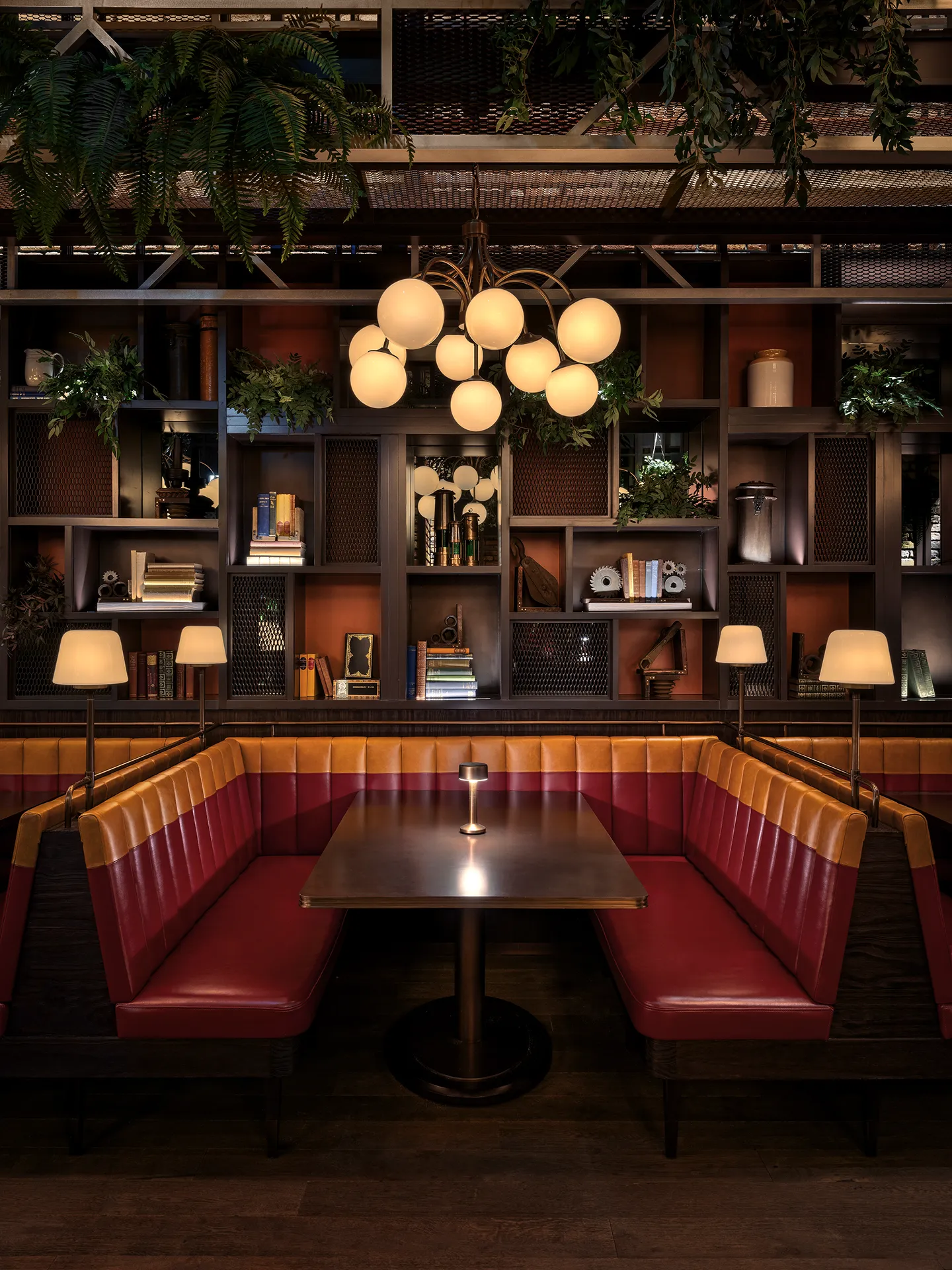 Red leather booth at Broadway, Emirates Palace Abu Dhabi, beneath a globe pendant chandelier and a timber display shelf wall