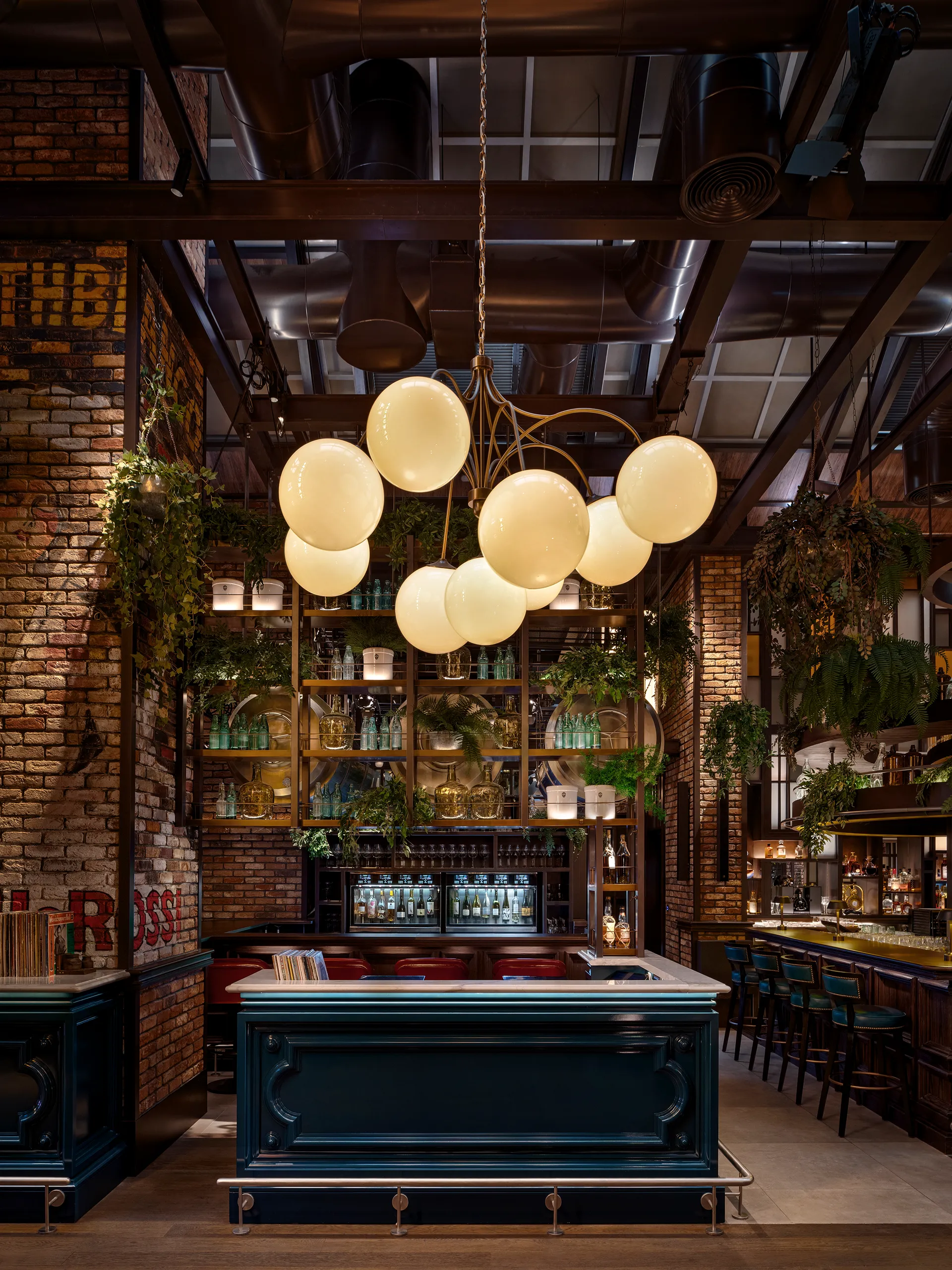DJ booth at Broadway, Emirates Palace Abu Dhabi, with a teal panelled booth, globe pendant chandelier and exposed brick walls