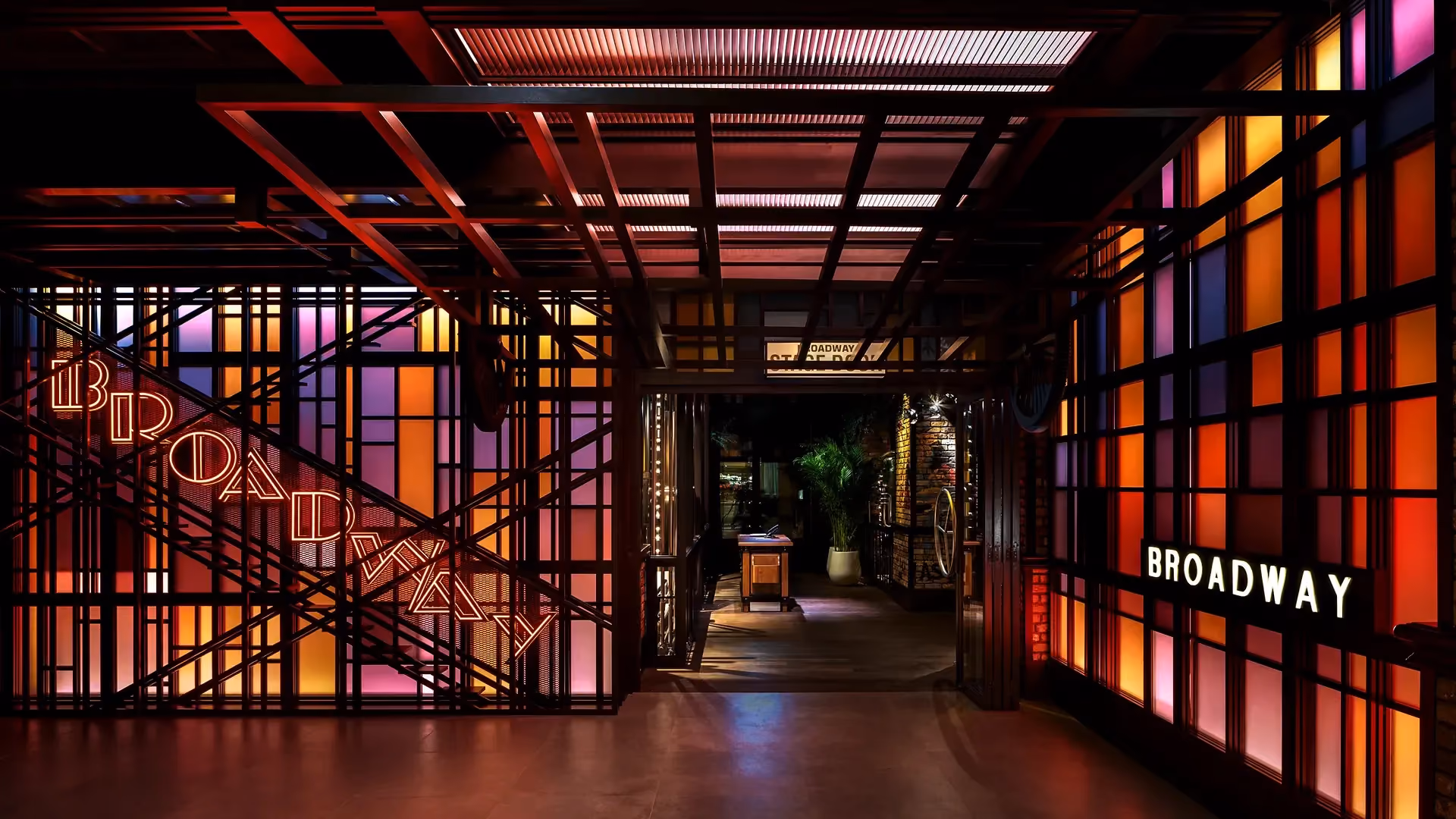 Entrance to Broadway at Emirates Palace Abu Dhabi, with neon Broadway signage on a fire escape staircase frame and backlit coloured glass panels