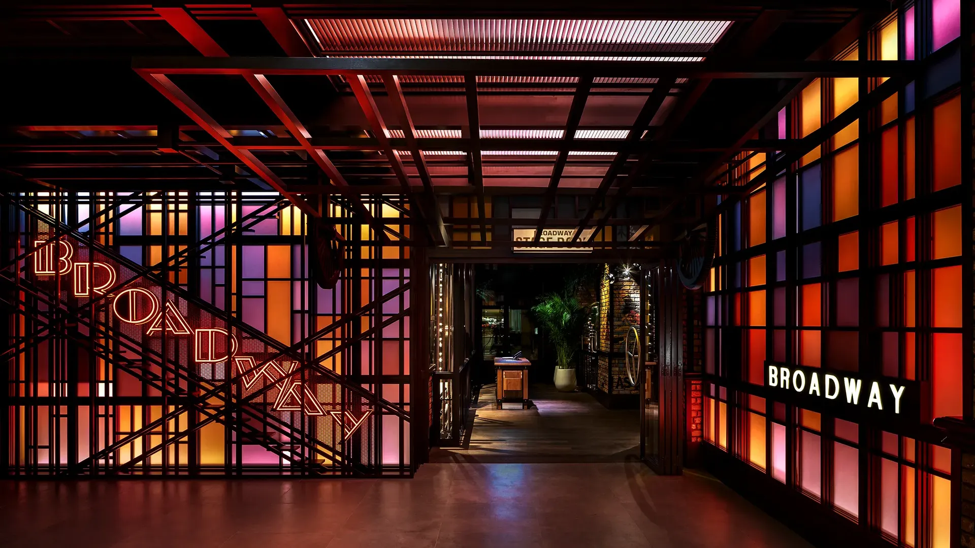 Entrance to Broadway at Emirates Palace Abu Dhabi, with neon Broadway signage on a fire escape staircase frame and backlit coloured glass panels