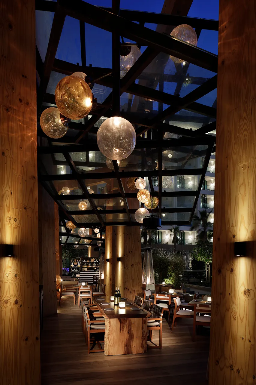 Outdoor dining terrace at Netsu, Mandarin Oriental Jumeira Dubai, with timber columns, a steel and glass canopy and hand-blown glass globe lamps