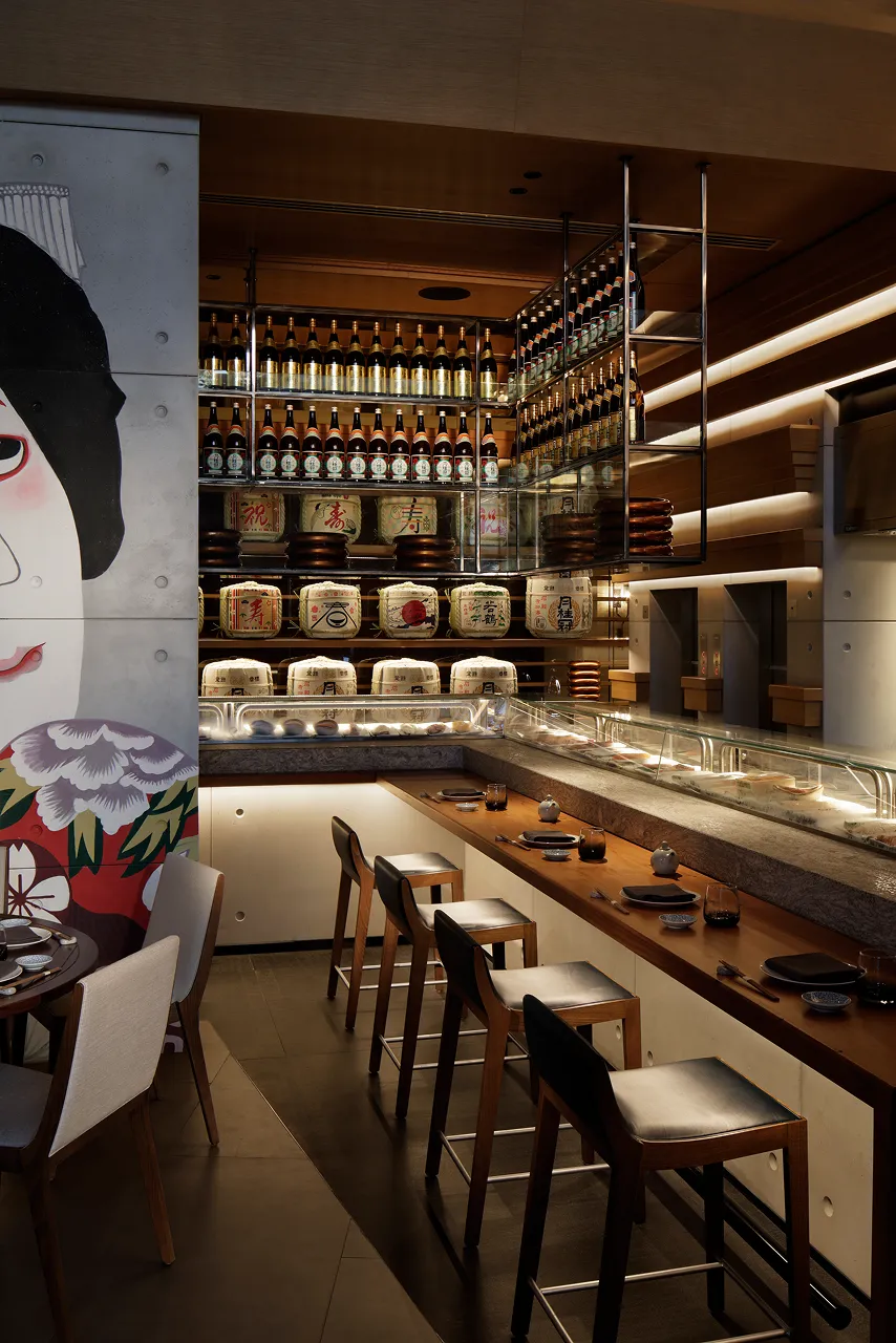 Sushi and sake bar at Netsu, Mandarin Oriental Jumeira Dubai, with a kabuki portrait mural, sake barrel display shelving and counter seating