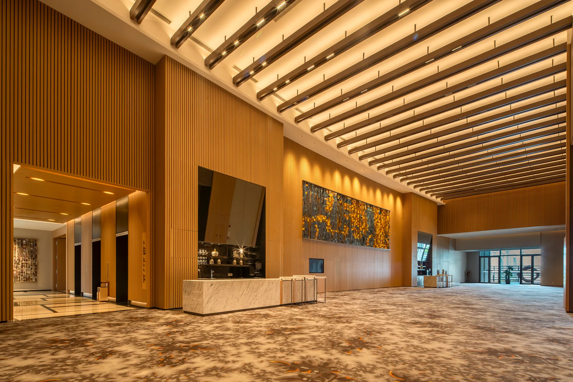Pre-function corridor at Hyatt Regency Hengqin with tall timber slats and ceiling cross-beams