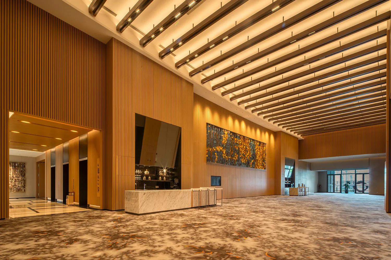 Pre-function corridor at Hyatt Regency Hengqin with tall timber slats and cross-beam ceiling