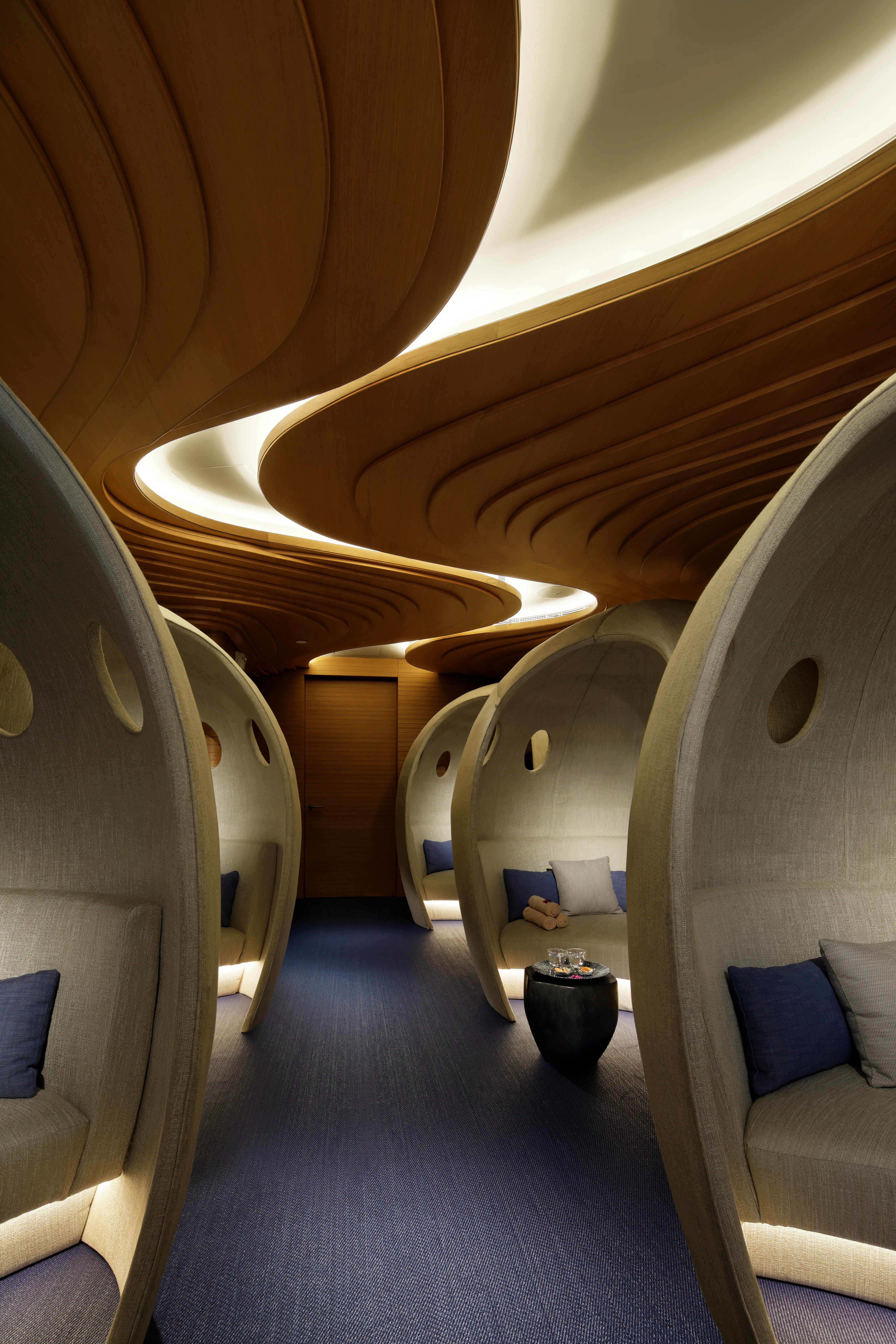 Relaxation lounge at The Spa, Mandarin Oriental Jumeira Dubai, with cocoon-shaped linen seating pods beneath a curved timber ceiling