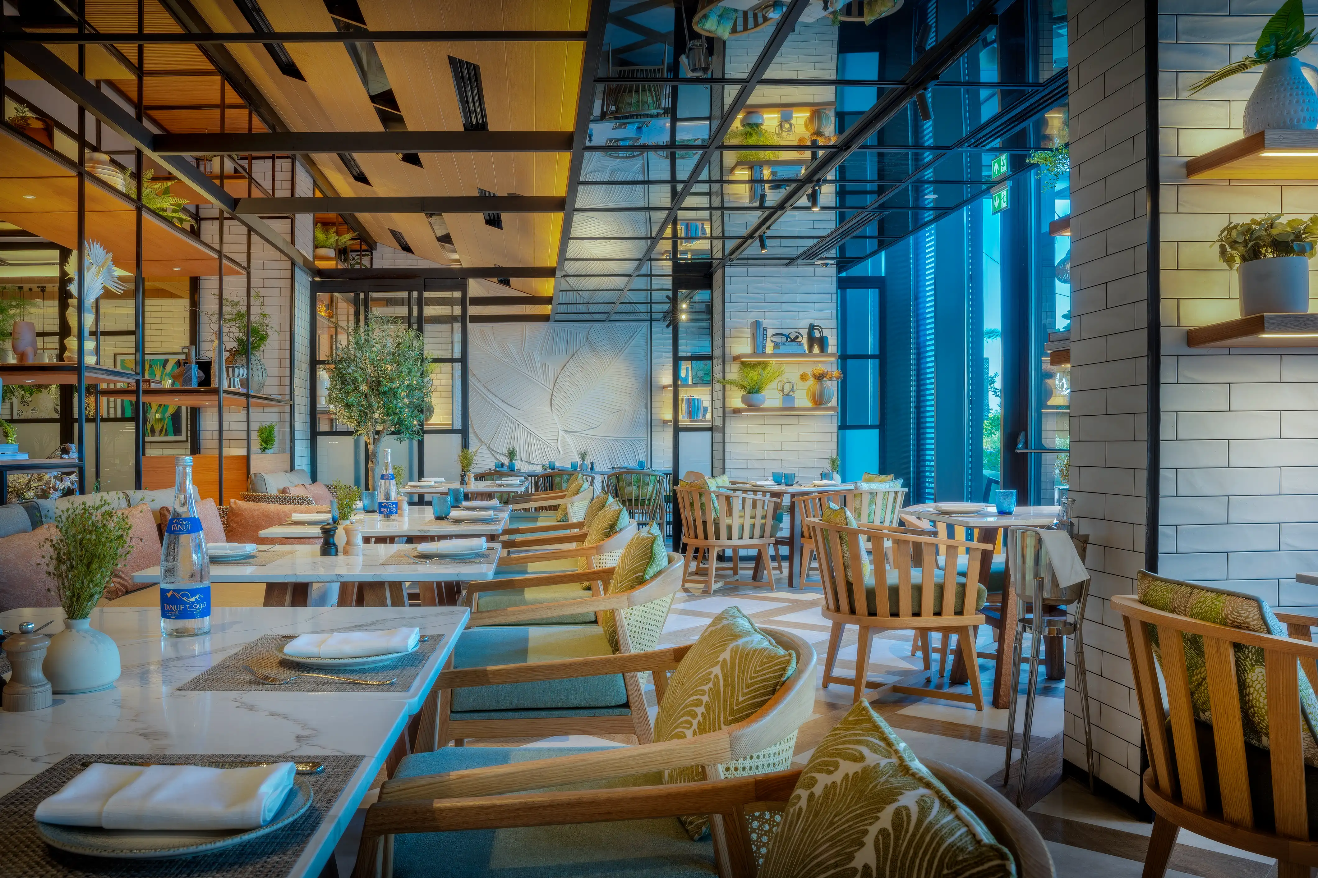 Veranda with a sloping timber ceiling, steel and glass framing, and timber and rattan chairs at Rawya, Mandarin Oriental, Muscat