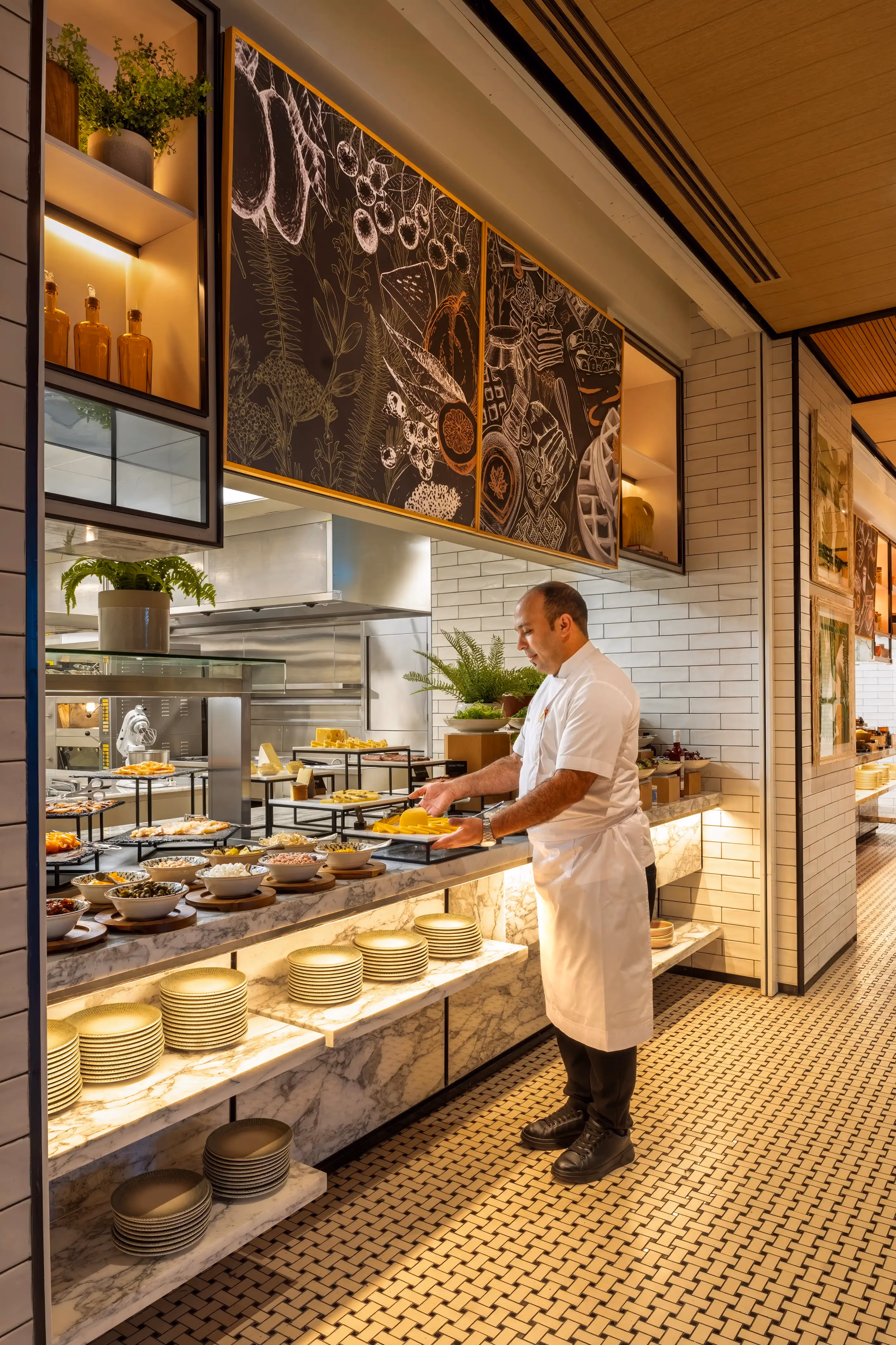 Chef at the open kitchen buffet counter with marble shelving, white tiles and chalkboard artwork at Rawya, Mandarin Oriental, Muscat