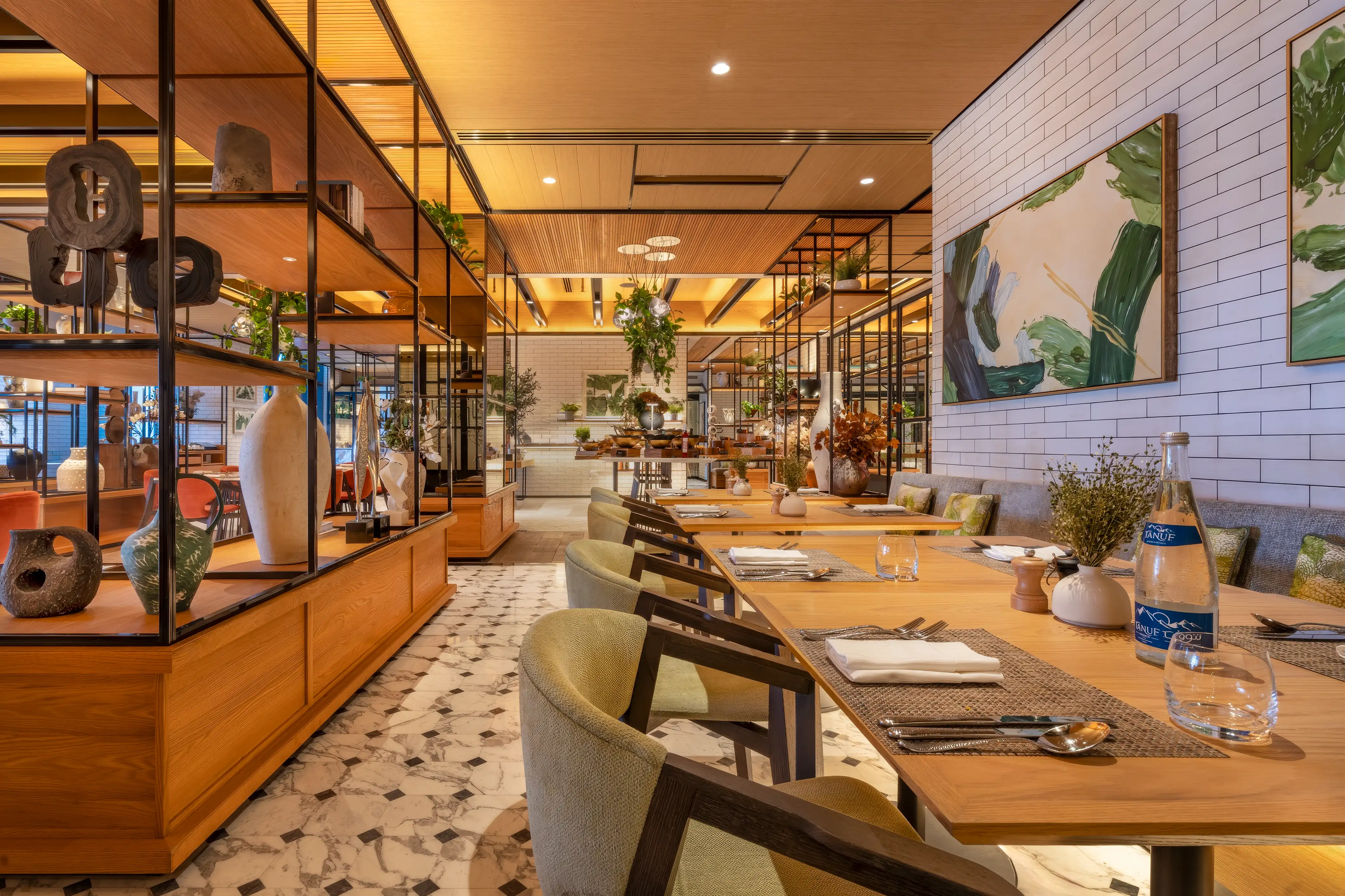 Dining hall with black steel shelving, a white tiled wall with botanical artwork and patterned floor tiles at Rawya, Mandarin Oriental, Muscat