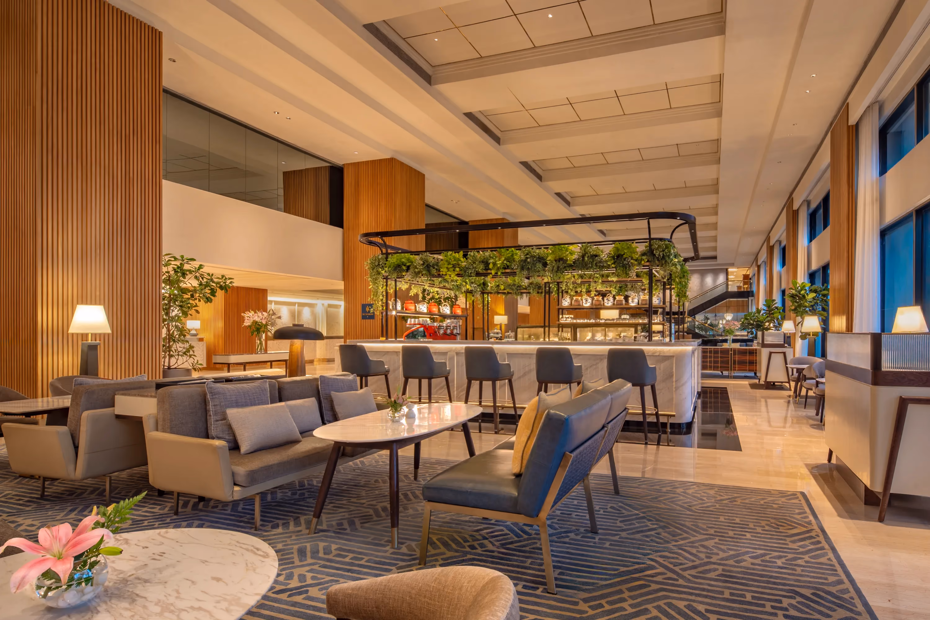 Grey sofas and armchairs on a patterned carpet facing the lobby lounge bar at Trident, Nariman Point, Mumbai