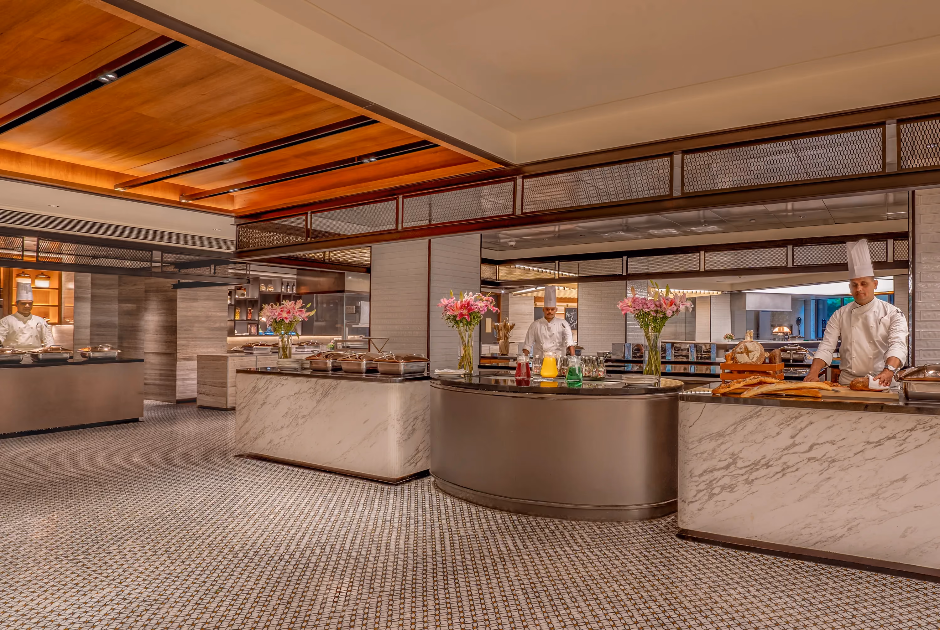 Chefs serving from marble-clad live food stations under a timber ceiling in the breakout area at Trident, Nariman Point