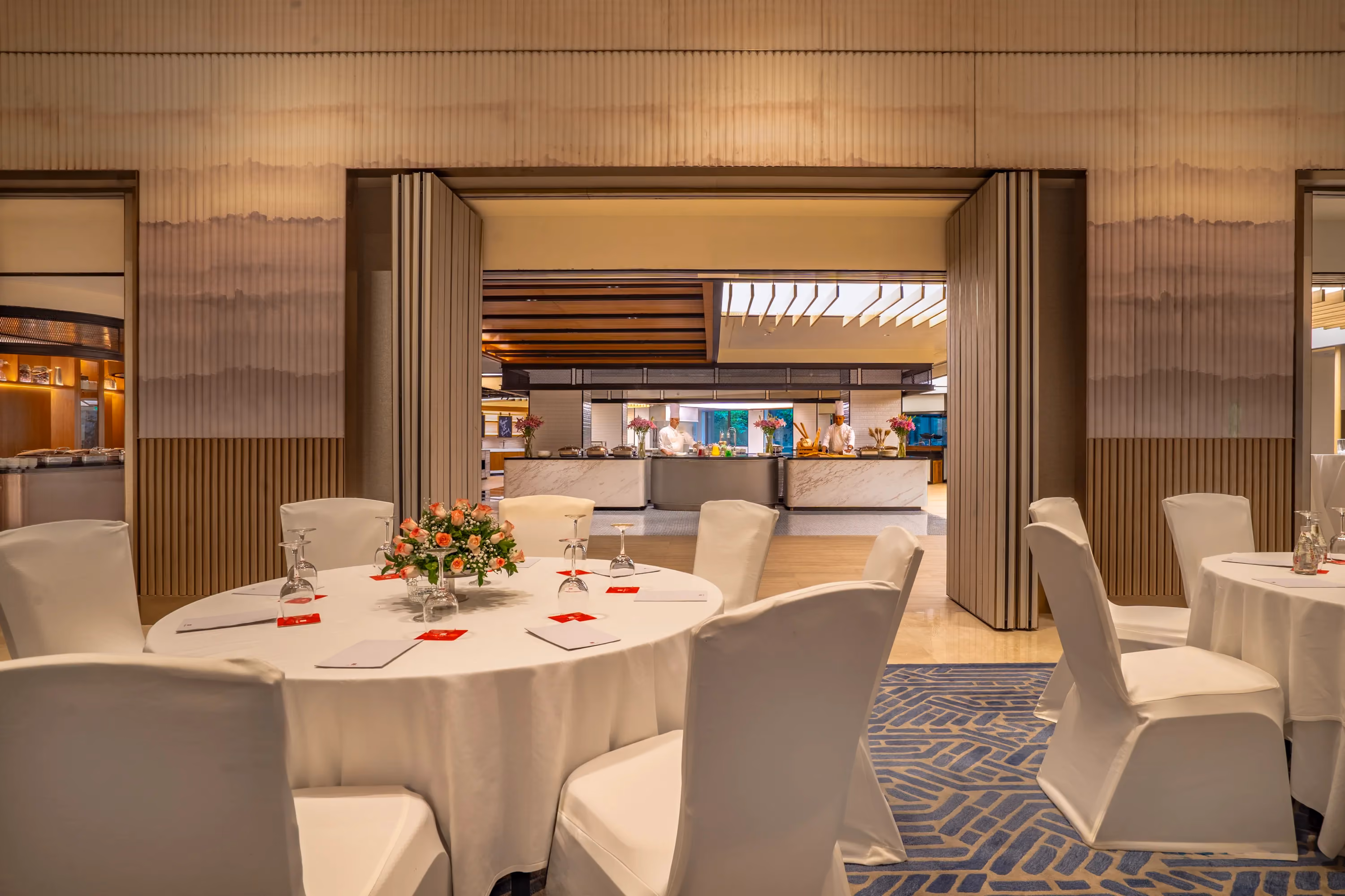 Round banquet table laid for dining, with folding partitions opening onto food stations, at Trident, Nariman Point