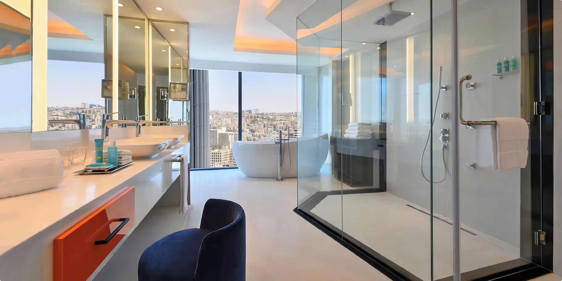 W Amman bathroom with a freestanding bathtub by the window, a glass rain shower and an orange fronted vanity