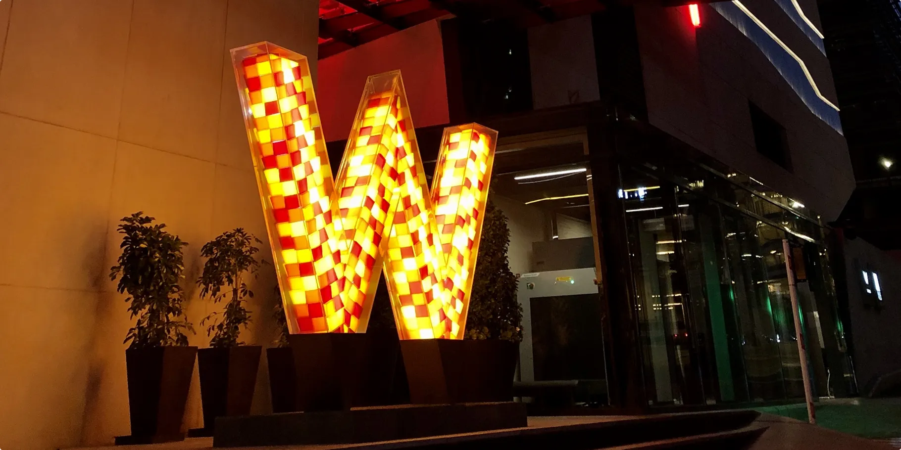 Illuminated red and amber mosaic W sign at the entrance of W Amman