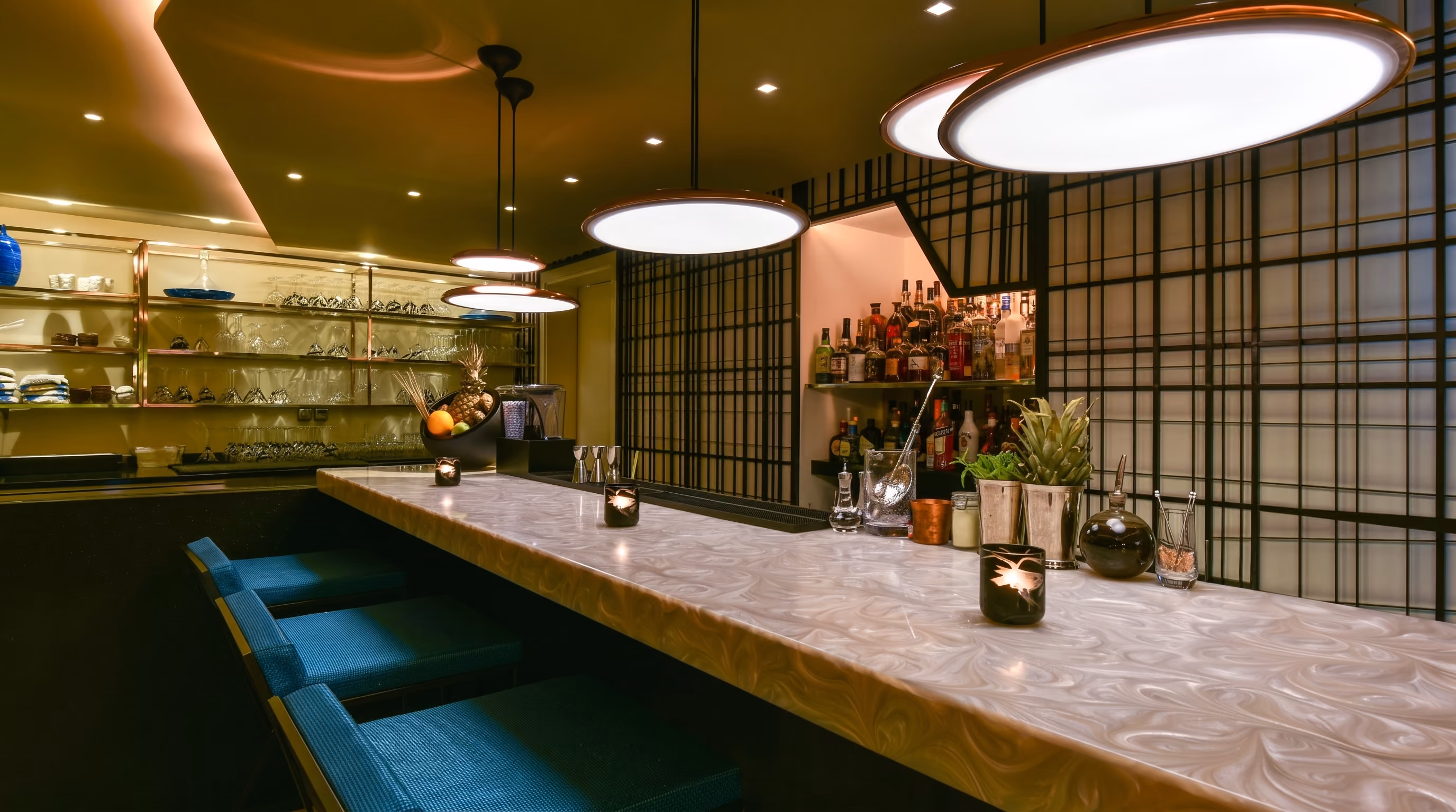 Enso bar at W Amman with a backlit stone counter, teal bar stools, a black lattice screen and large disc pendant lights