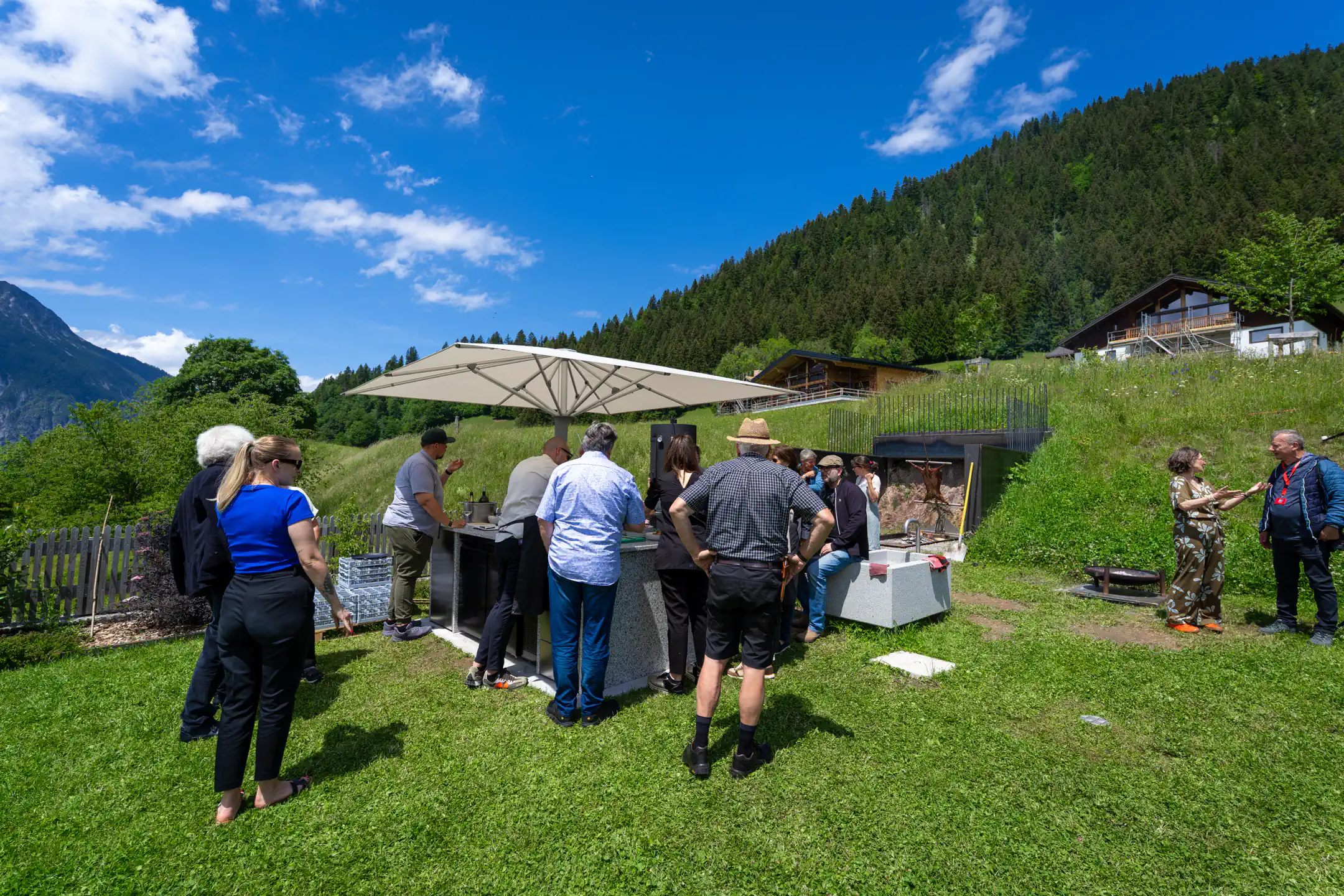 Gäste versammeln sich bei Verner's auf der Wiese rund um die Feuerstelle