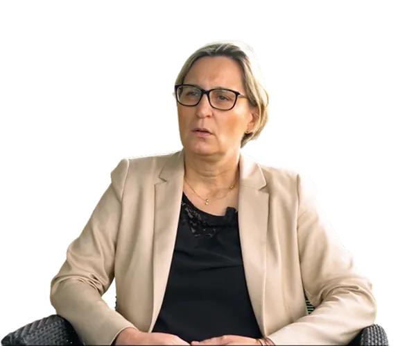 Femme portant des lunettes et un blazer beige, assise et discutant.