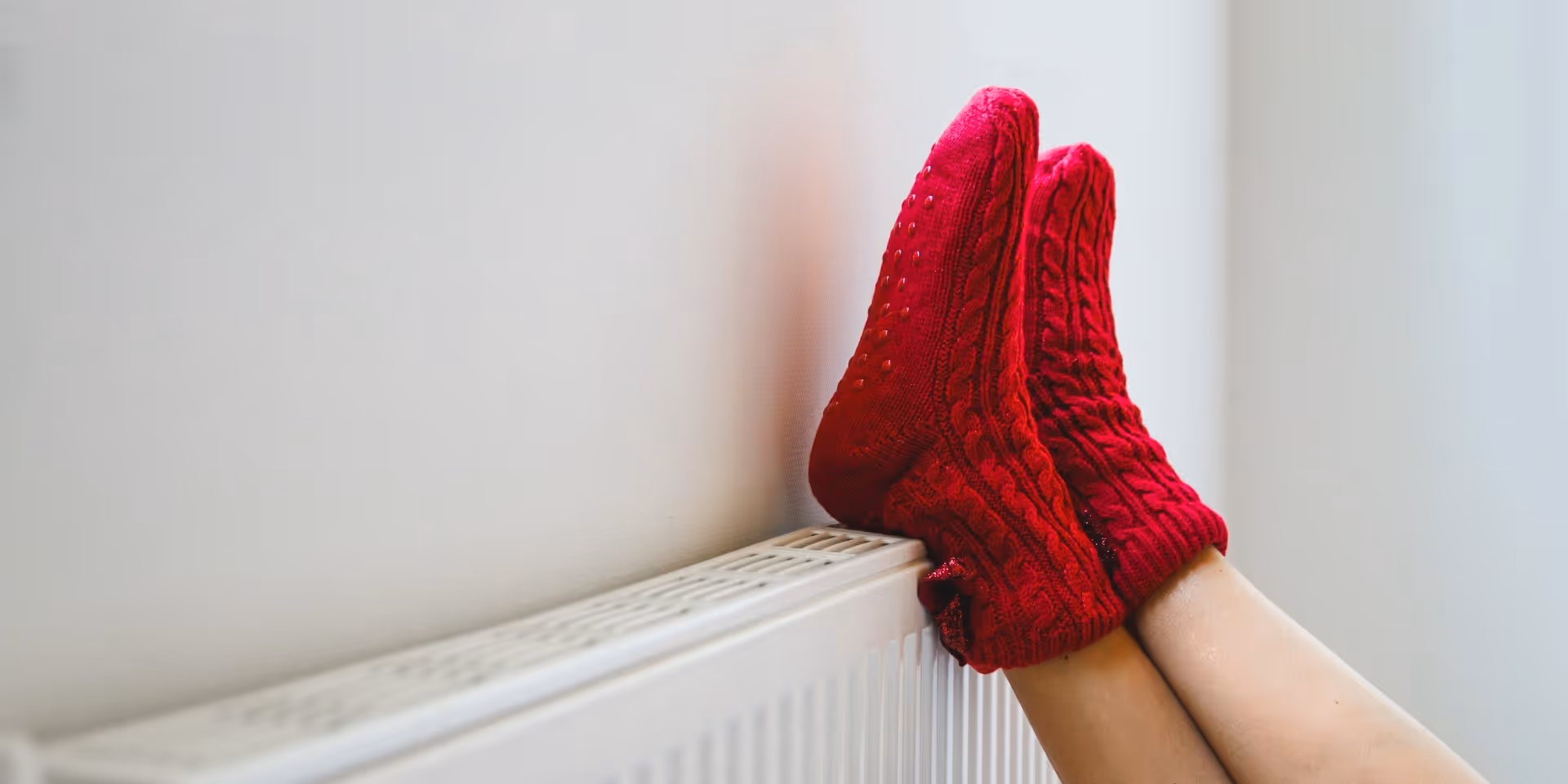 Frau mit roten Socken legt Füße auf einen Heizkörper