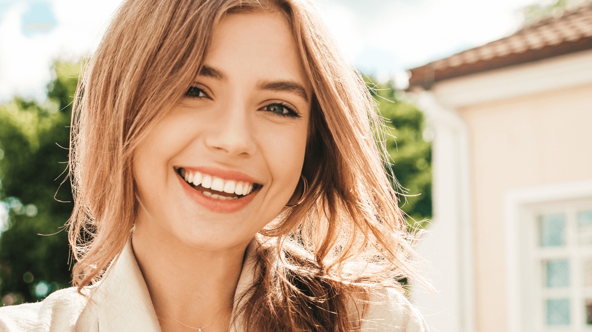 Smiling young woman with bright white teeth after treatment by the best cosmetic dentist in San Francisco.