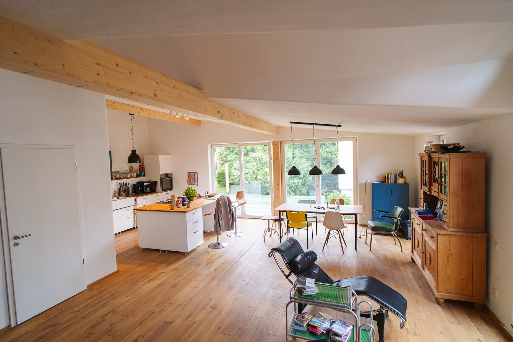 Offener Wohn-Essbereich nach Innenausbau von Takatukabau: Holzfußboden, freier Leimbinder und Blick in den Garten.