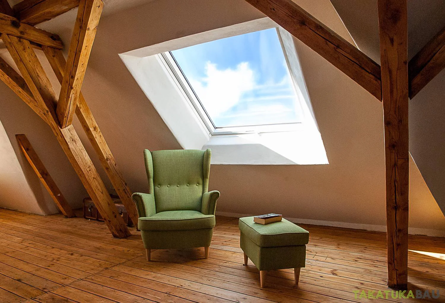 Dachgeschosslounge mit sichtbaren Balken, großem Dachfenster und grünem Sessel – Holz- und Lehm-Innenausbau von Takatukabau.