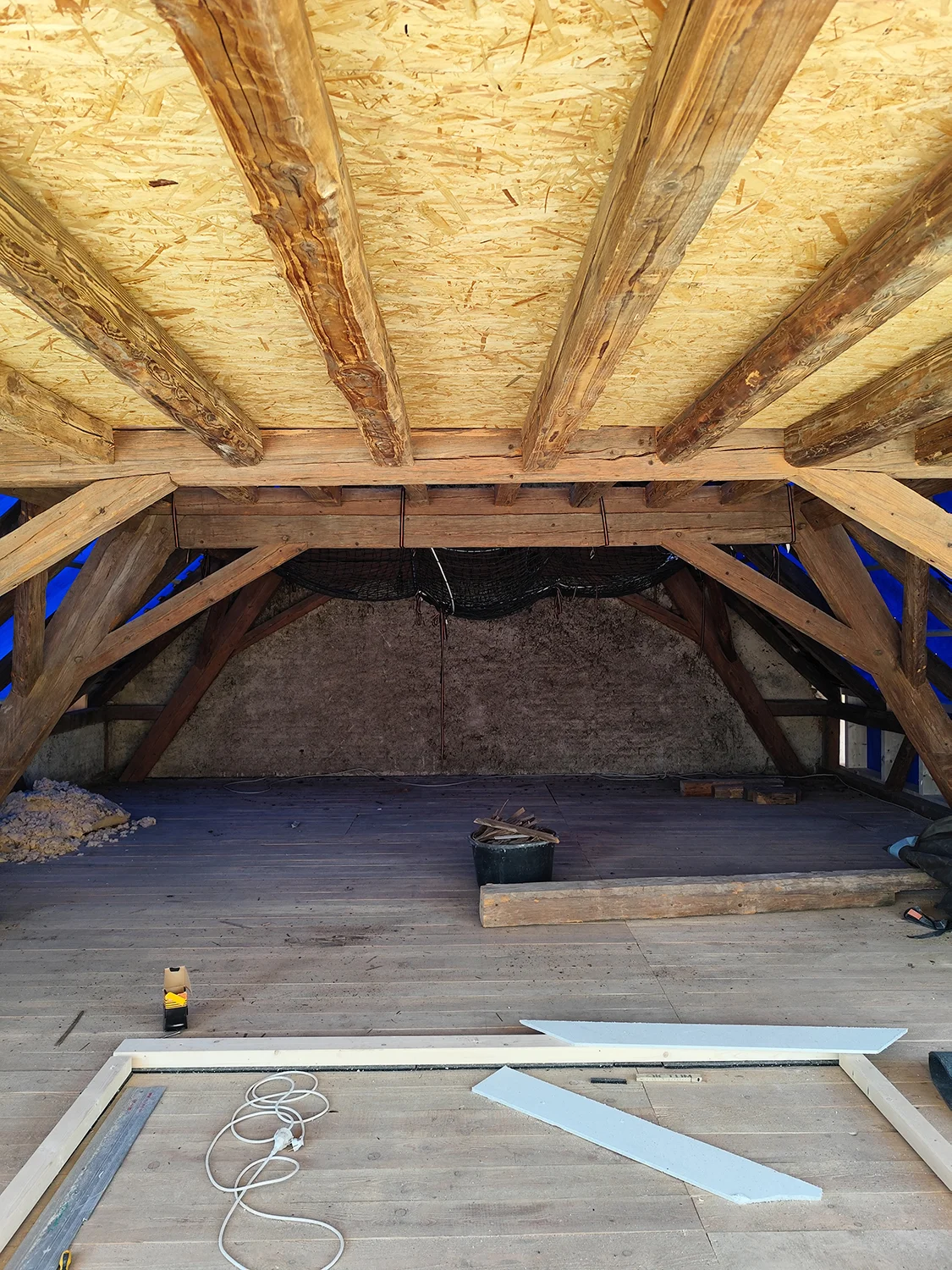 Ausbau Dachstuhl: freigelegte Fachwerkbalken und neue OSB-Schalung im leeren Dachboden, Sanierungsprojekt von Takatukabau.