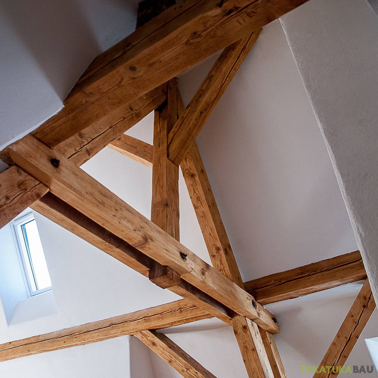 Saniertes Sichtgebälk: gereinigte Eichenbalken mit neuem Dachfenster im frisch verputzten Dachraum von Takatukabau.