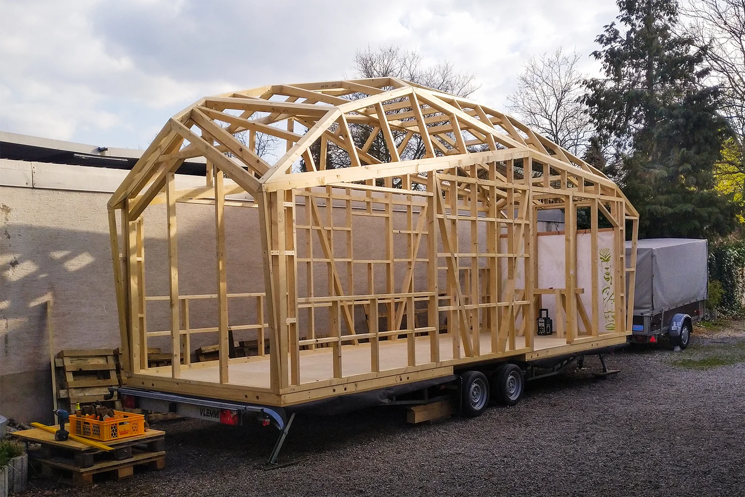 Kran setzt Holzmodul auf Dach; zwei Zimmerer von Takatukabau koordinieren die Montage hoch über Freiburgs Innenstadt.