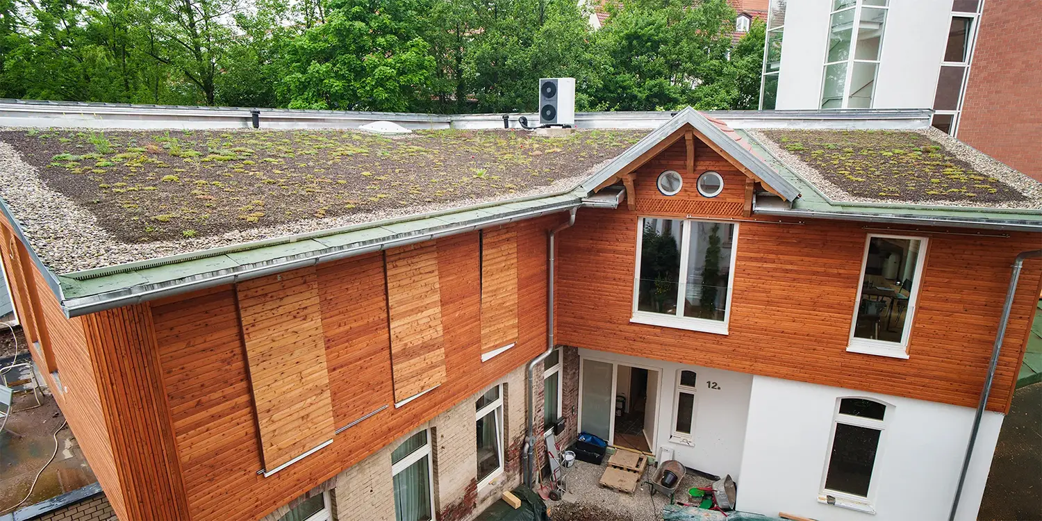Modernisiertes Wohnhaus in Freiburg mit Holzfassade und zwei Gründächern, umgesetzt von Takatukabau.
