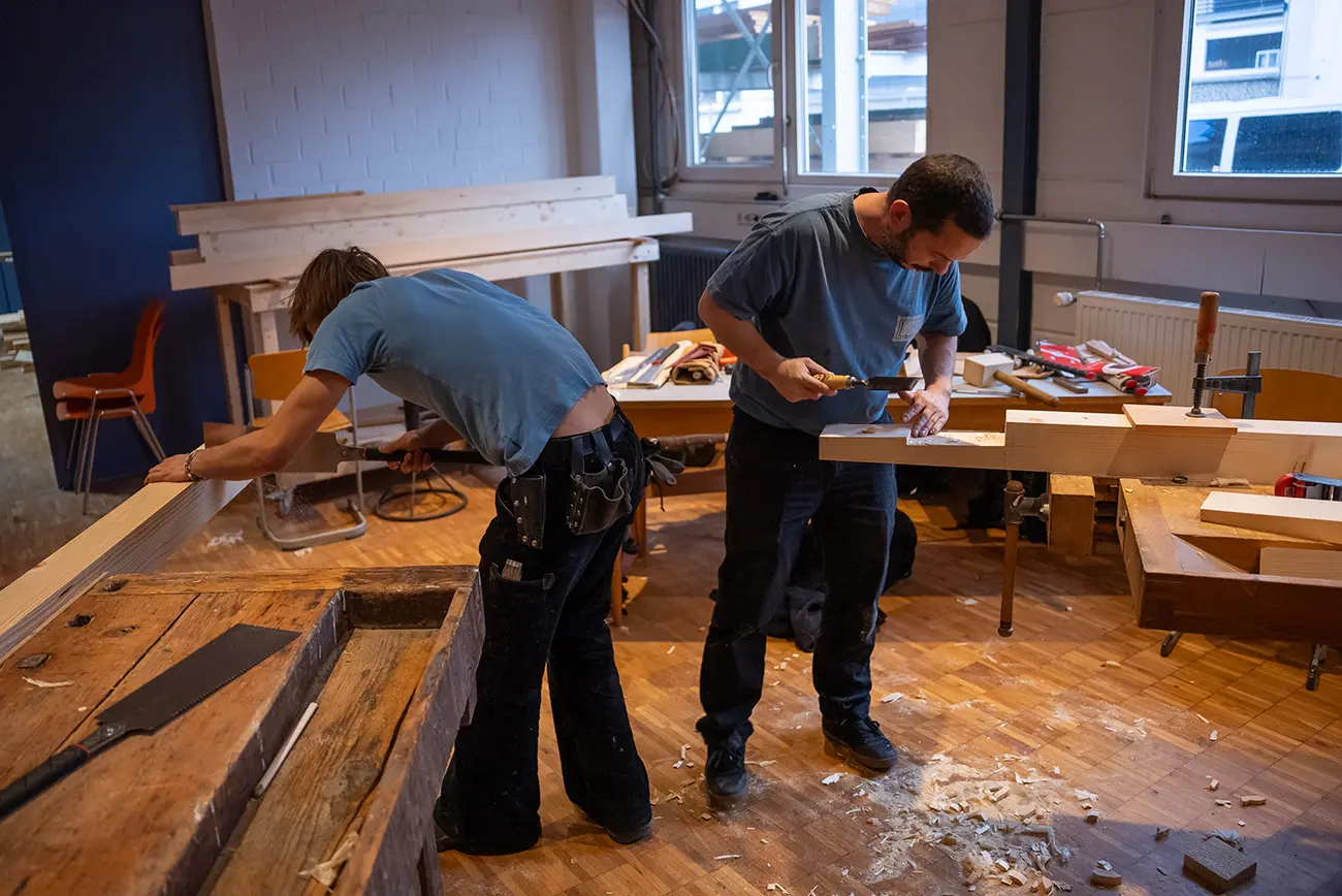 Teilnehmende bearbeiten Holz in einem Handwerkskurs in der HALLE Freiburg