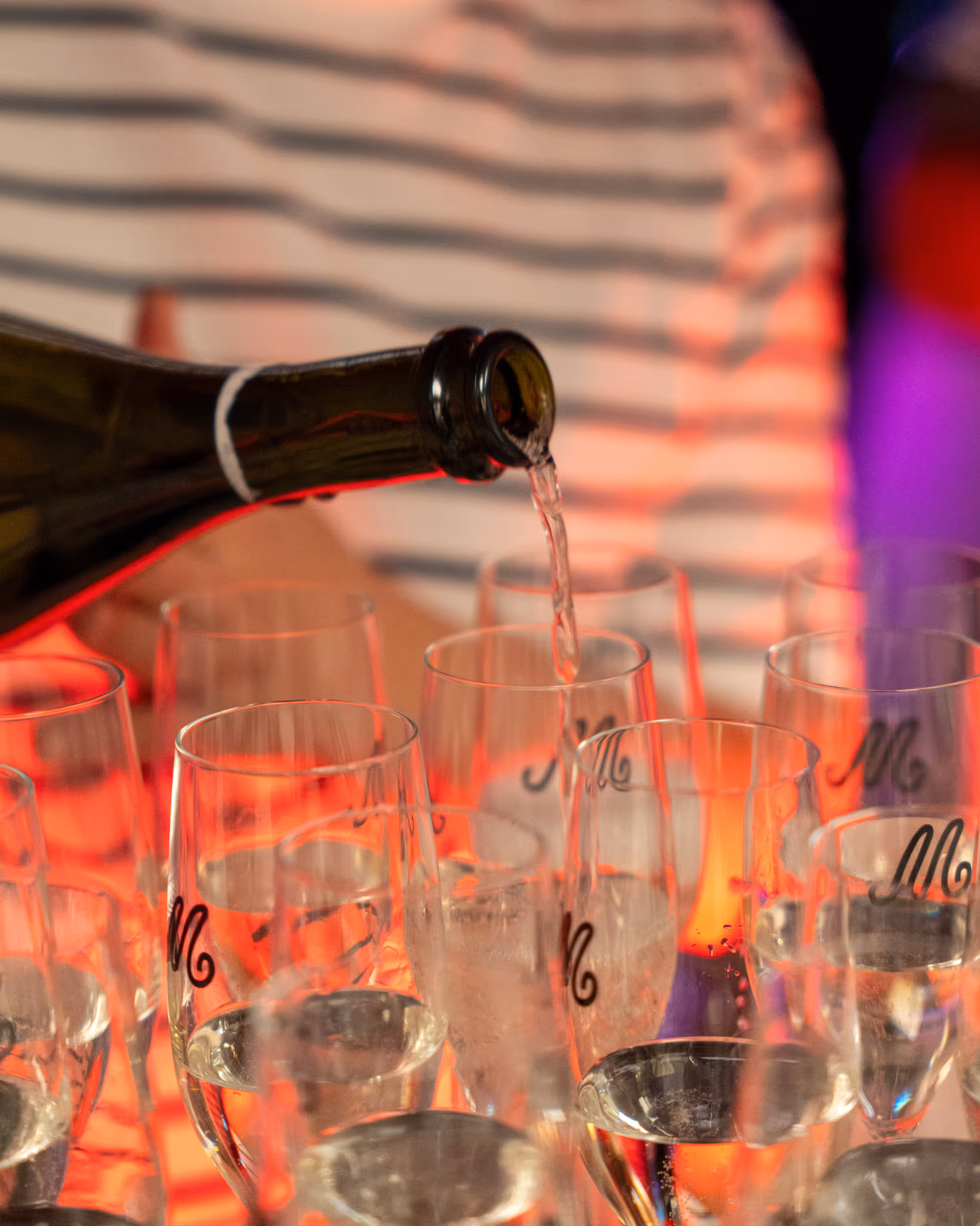 Sparkling wine being poured into glasses with the Madame logo.