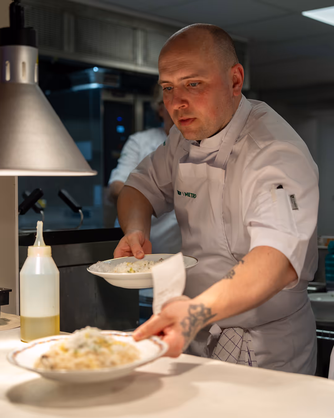 Chef at Restaurant Madame preparing and serving pasta dishes in the kitchen.