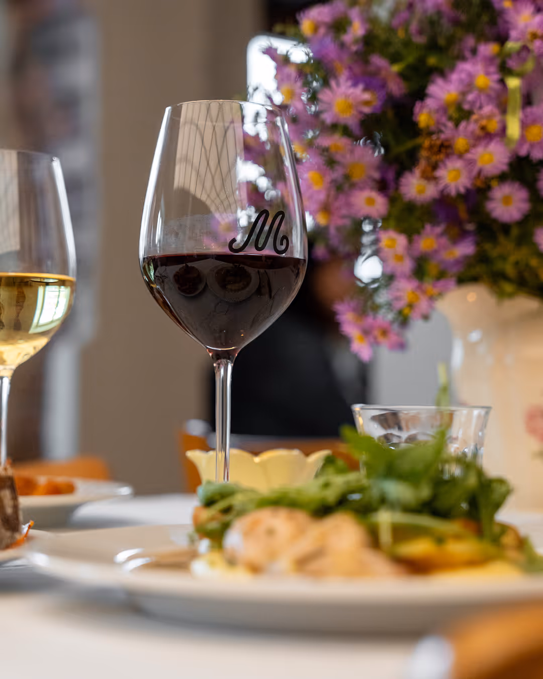 Plates of food, bread, and glasses of red and white wine on a table at Restaurant Madame.
