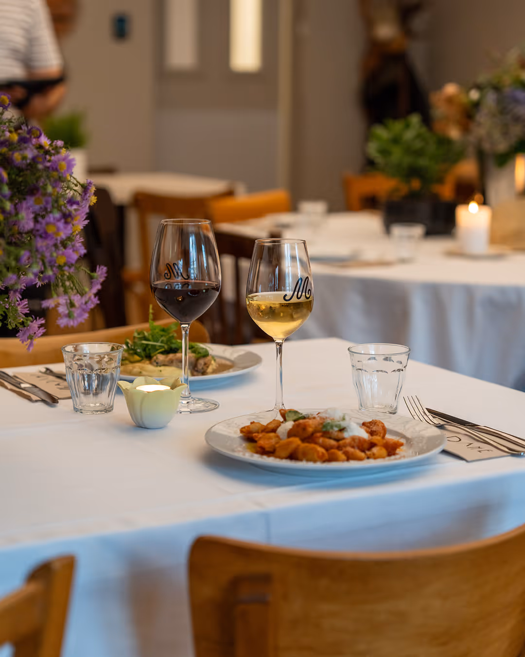 Plates of food, bread, and glasses of red and white wine on a table at Restaurant Madame.