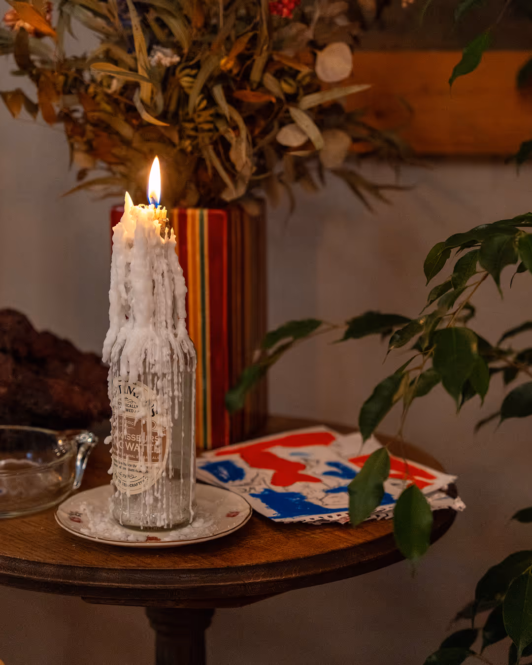  Candle burning in a glass bottle on a small wooden table at Restaurant Madame.