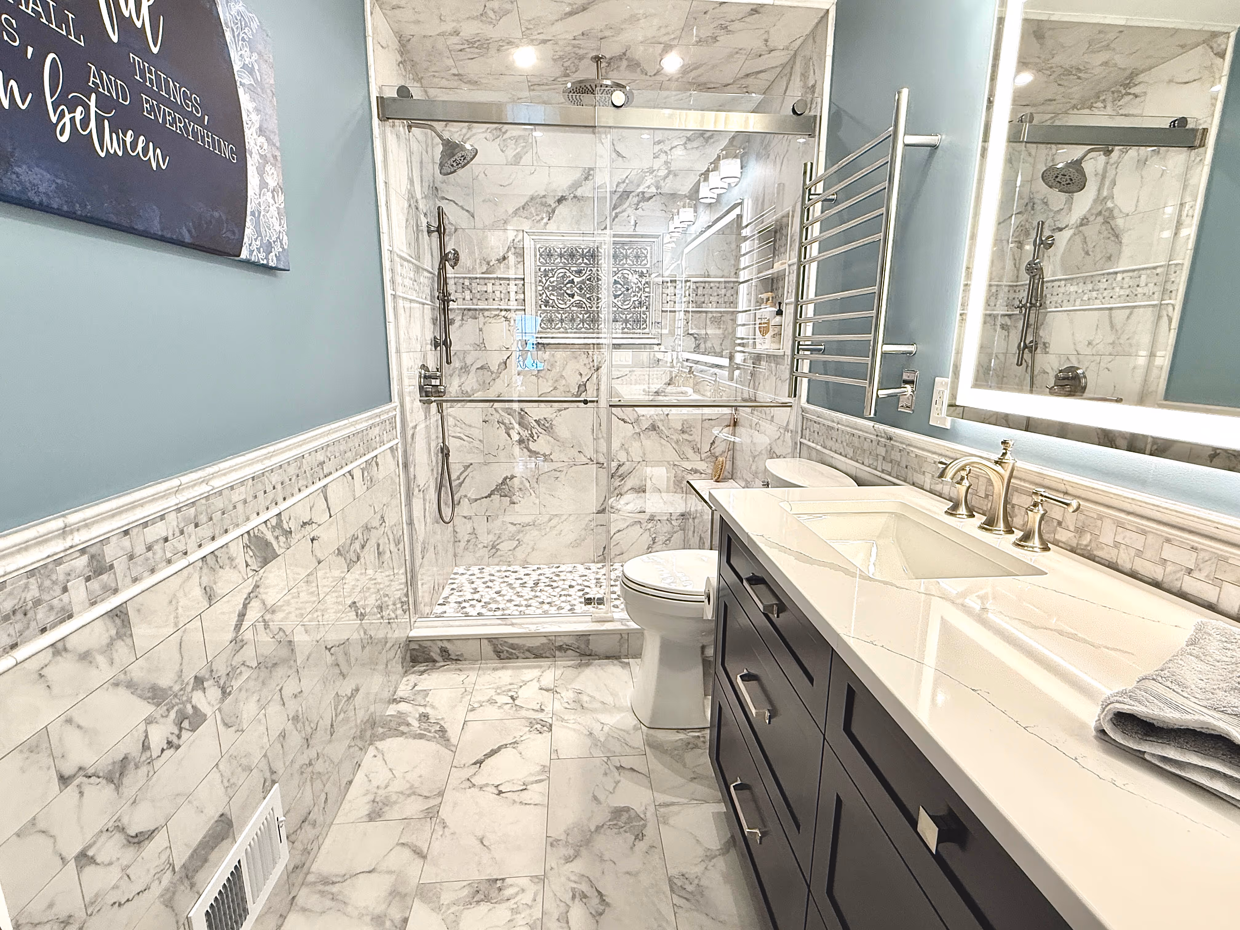 A bathroom with gray and white tile and vanity.