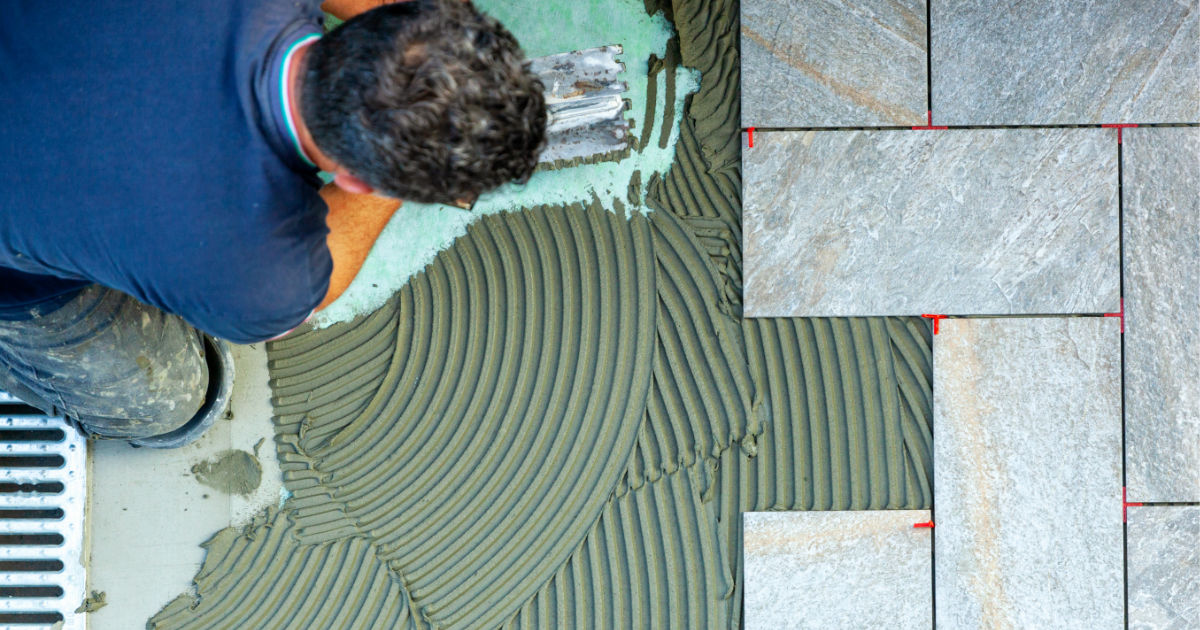 Man spreading thin-set mortar and installing tile