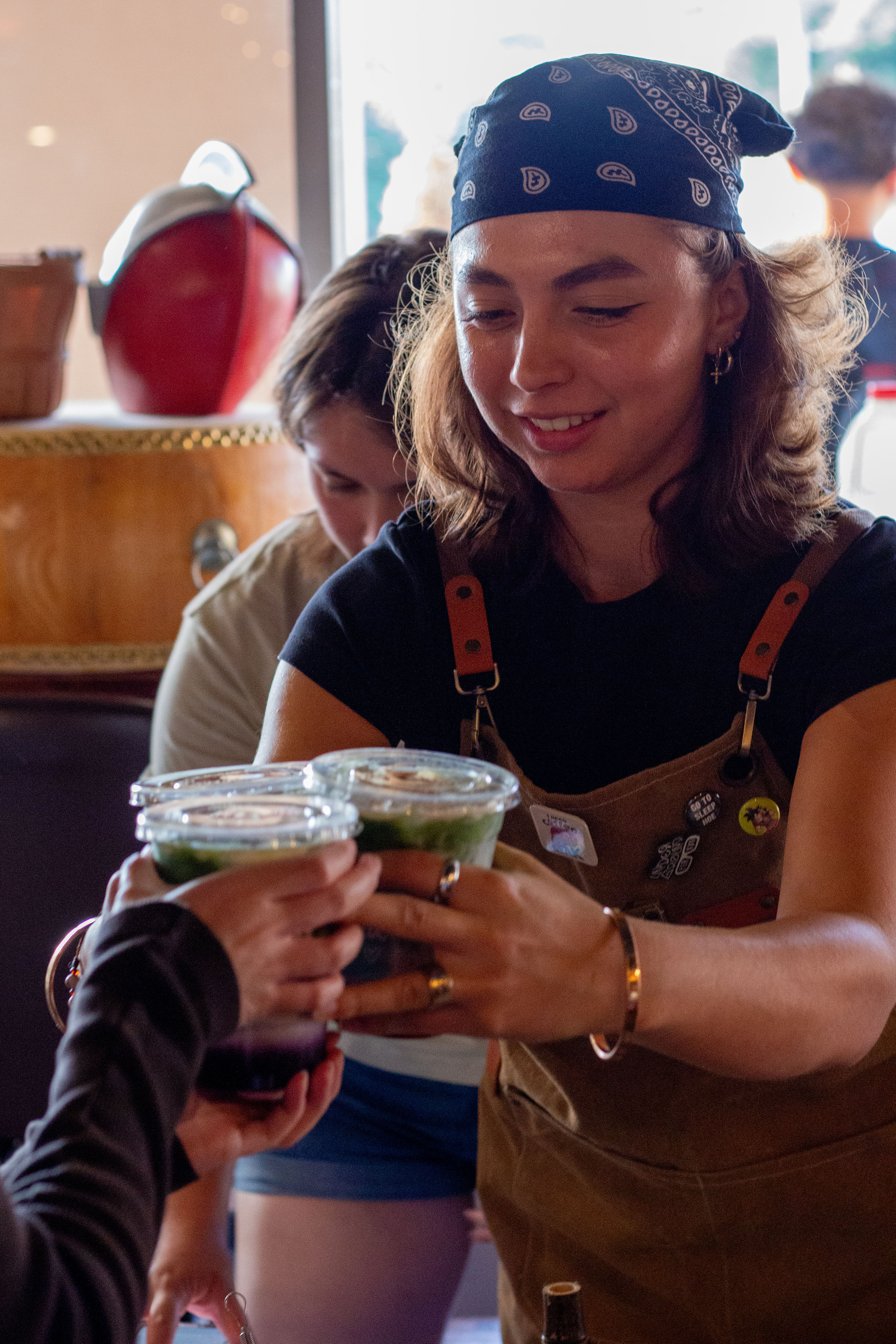 A Satcha employee hands customer 3 cups of matcha.