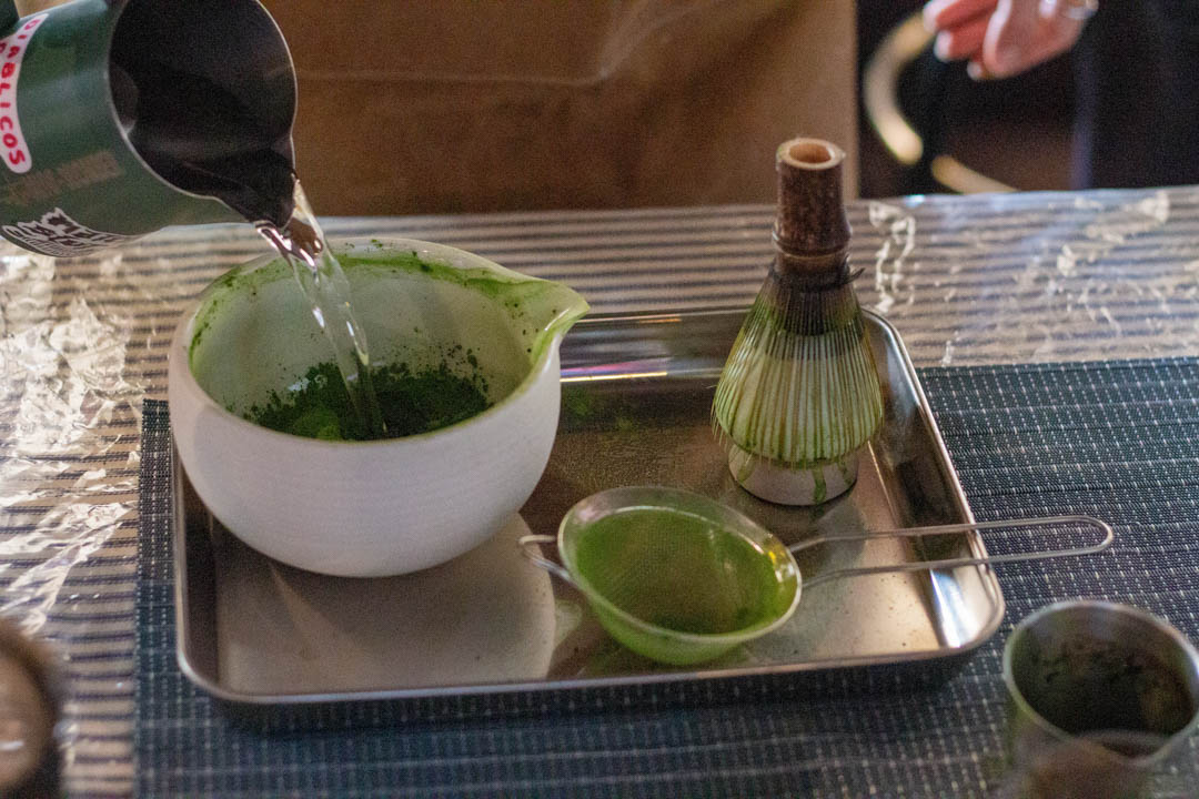 Cup of water being poured into matcha bowl.