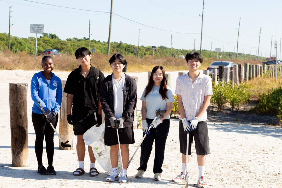 College students participating in The Welcome Standard's beach cleanup pose for a group photo.