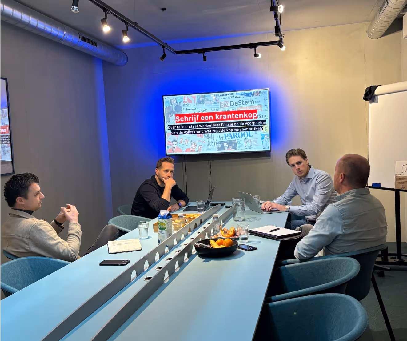 Pulse online marketing Sliedrecht team vergadert met krantenkoppen op scherm