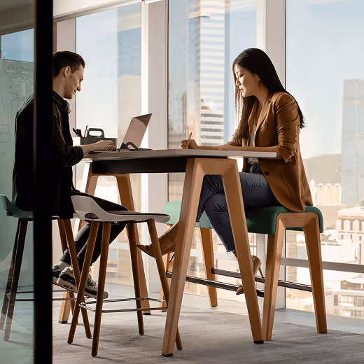 Two people sitting at a high table on their laptops