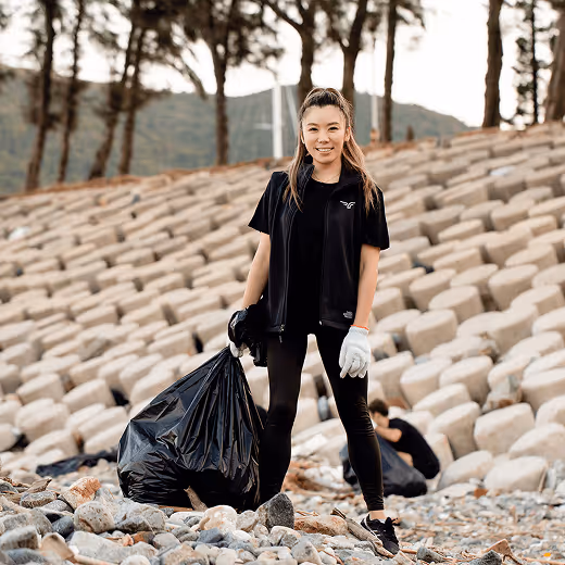 A woman holding rubbish bags outside in front of palm trees