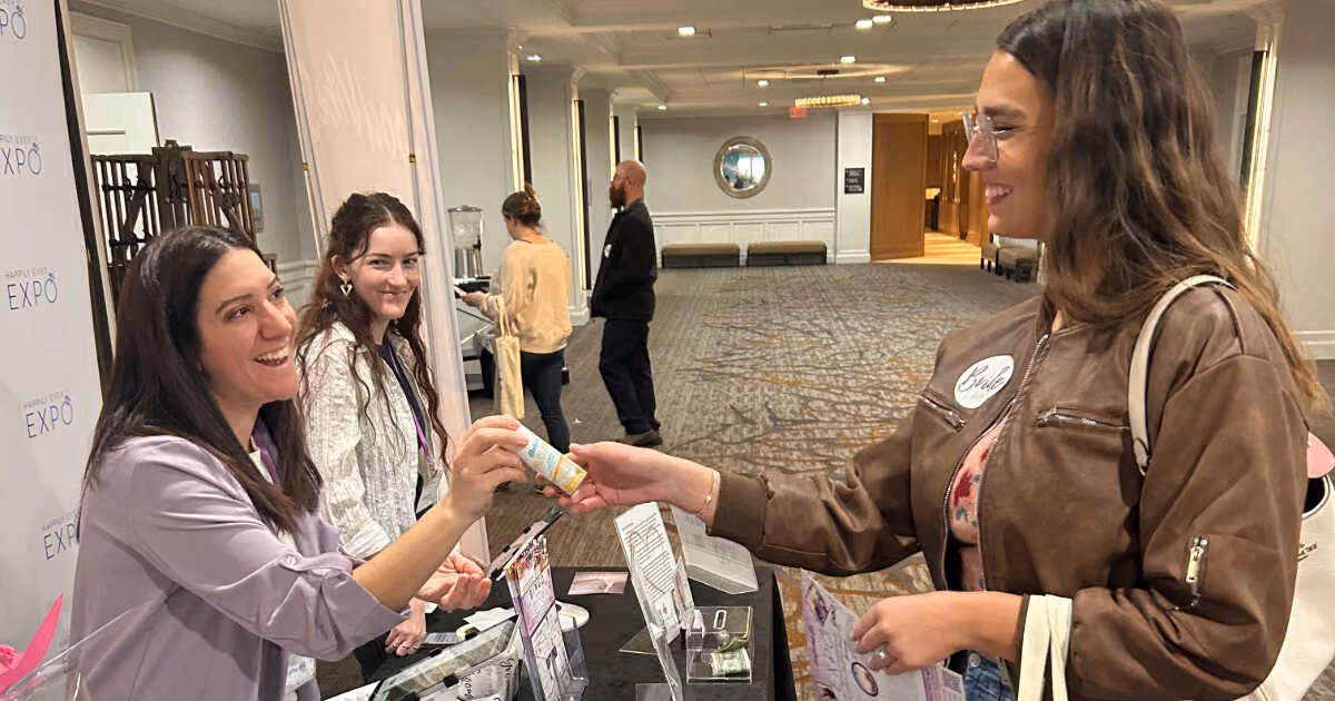 woman giving batiste sample to another woman