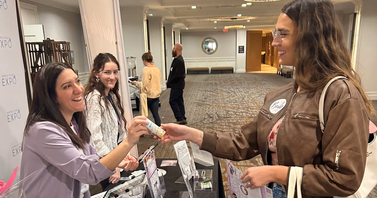 woman giving batiste sample to another woman