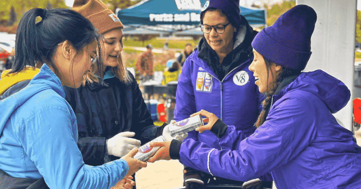 woman giving out V8 to two woman