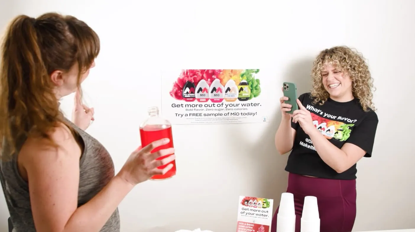 woman taking a pic of another woman holding mio sample