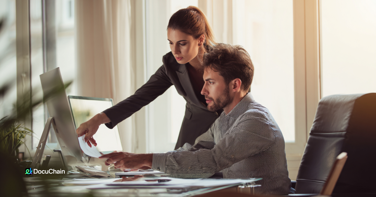 Woman helps colleague finalize documents on desktop, representing a transition from manual scanning to digital eSignature workflow with DocuChain